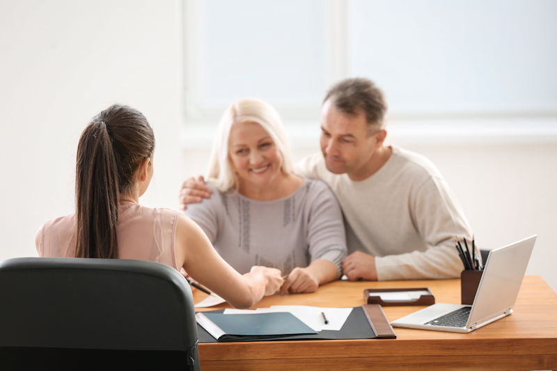 Couple consulting a professional woman at office desk with laptop.